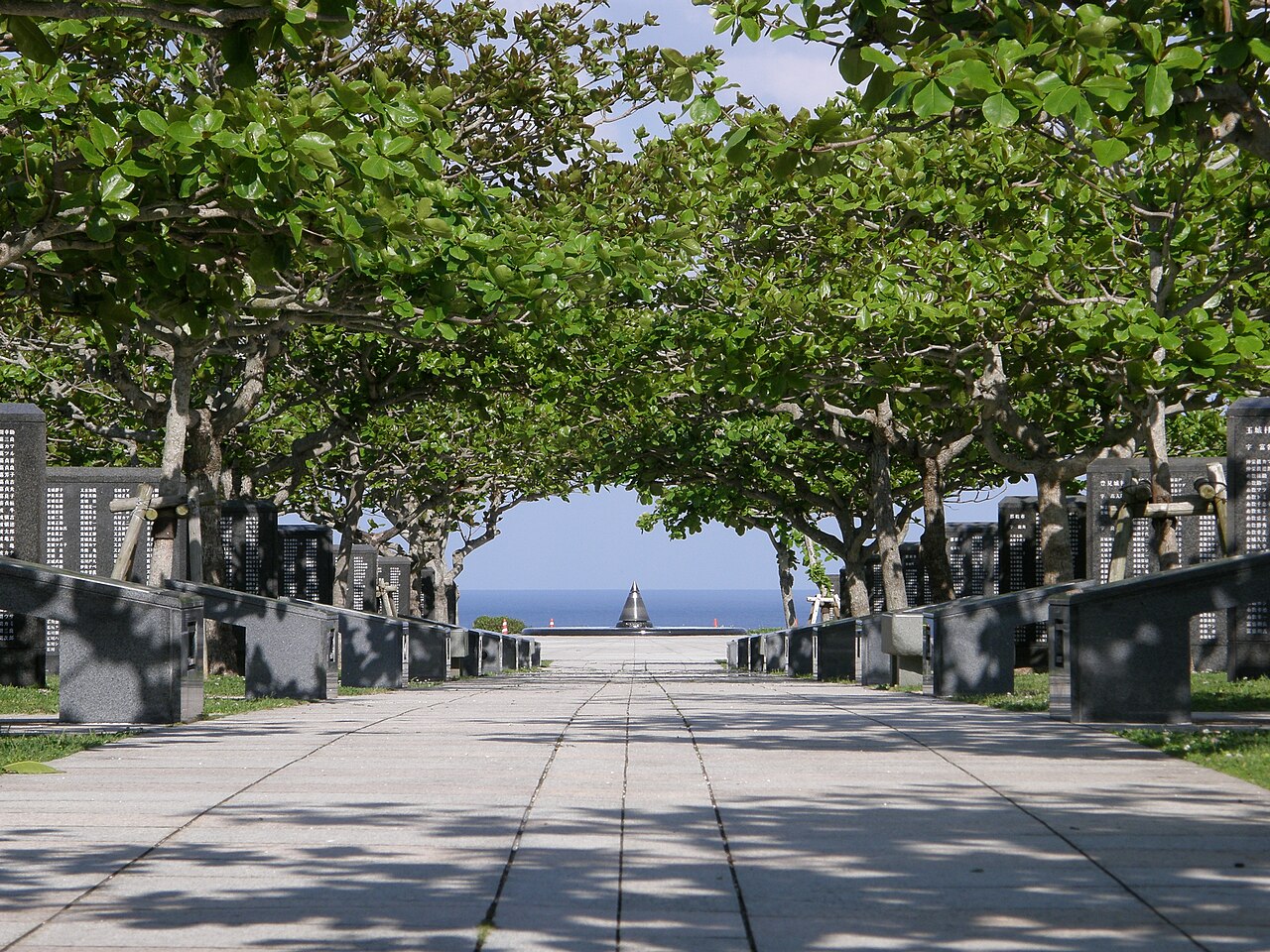 平和の礎の刻銘碑が並ぶ園路。海のほうへ向かって平和の火が見える（写真：Lequios-star / CC BY-SA 4.0）